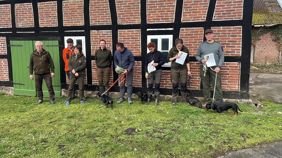 Teilnehmende der Prüfung der Gruppe Nassauer Land mit ihren Hunden vor einem Fachwerkhaus